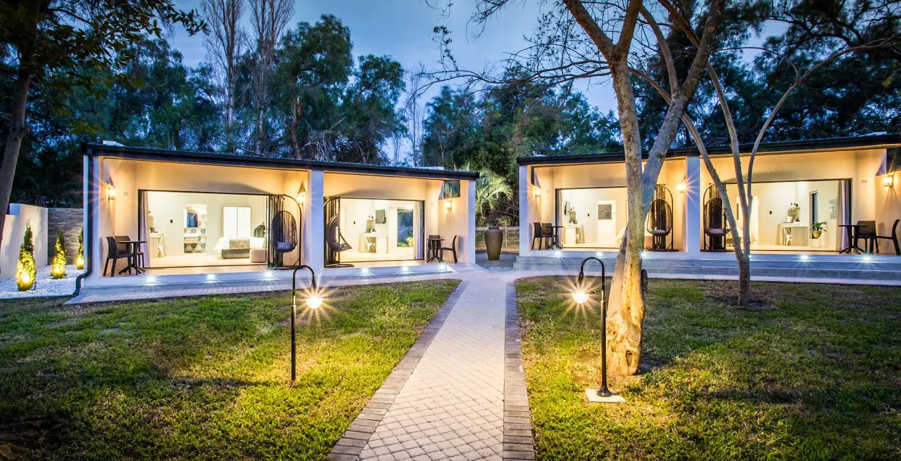 Hlangana Lodge guest rooms illuminated beside the garden at dusk